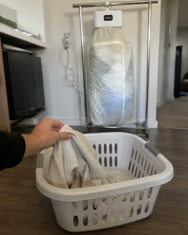 Sacando ropa del canasto frente a la secadora portatil funcionando